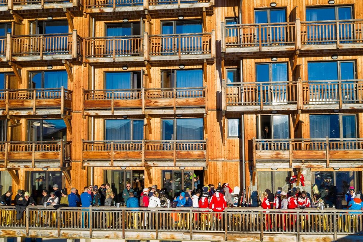 A group of people standing on a balcony in front of a wooden building