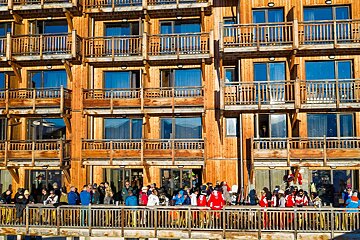 A group of people standing on a balcony in front of a wooden building