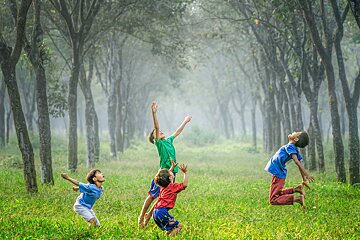 A group of children are playing in a field with trees in the background