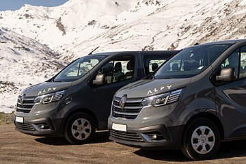 Two alpy vans are parked in front of a snowy mountain