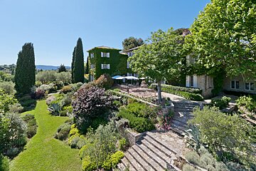 A large house is surrounded by a lush green garden