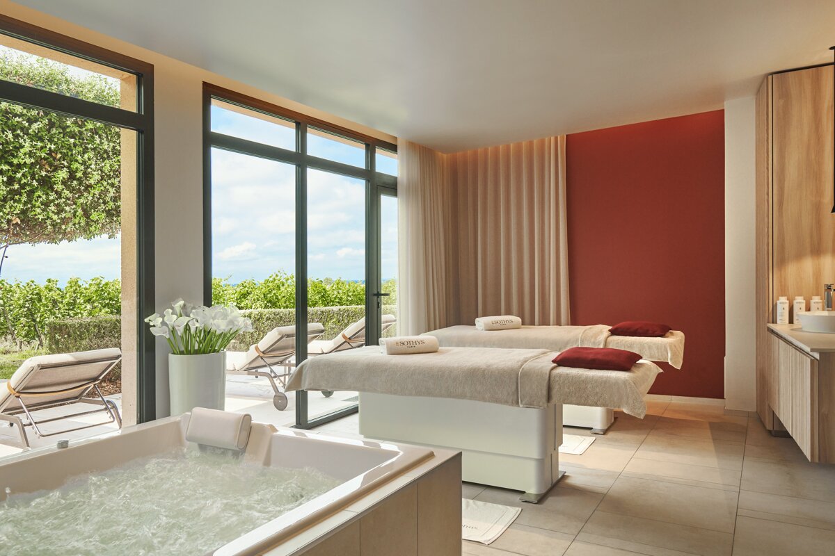 A spa room with two massage tables and a bathtub