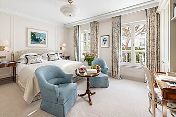 A hotel room with a large bed and two chairs