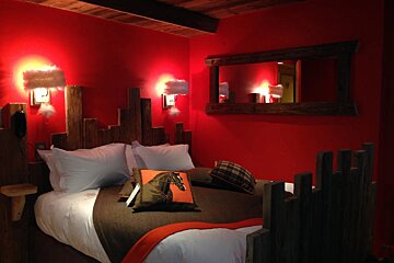 A bedroom with red walls and a wooden headboard