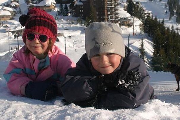 A boy and a girl are laying in the snow