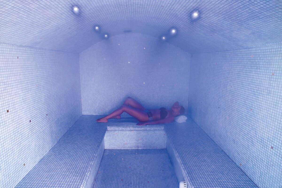 A woman is laying down in a blue tiled room