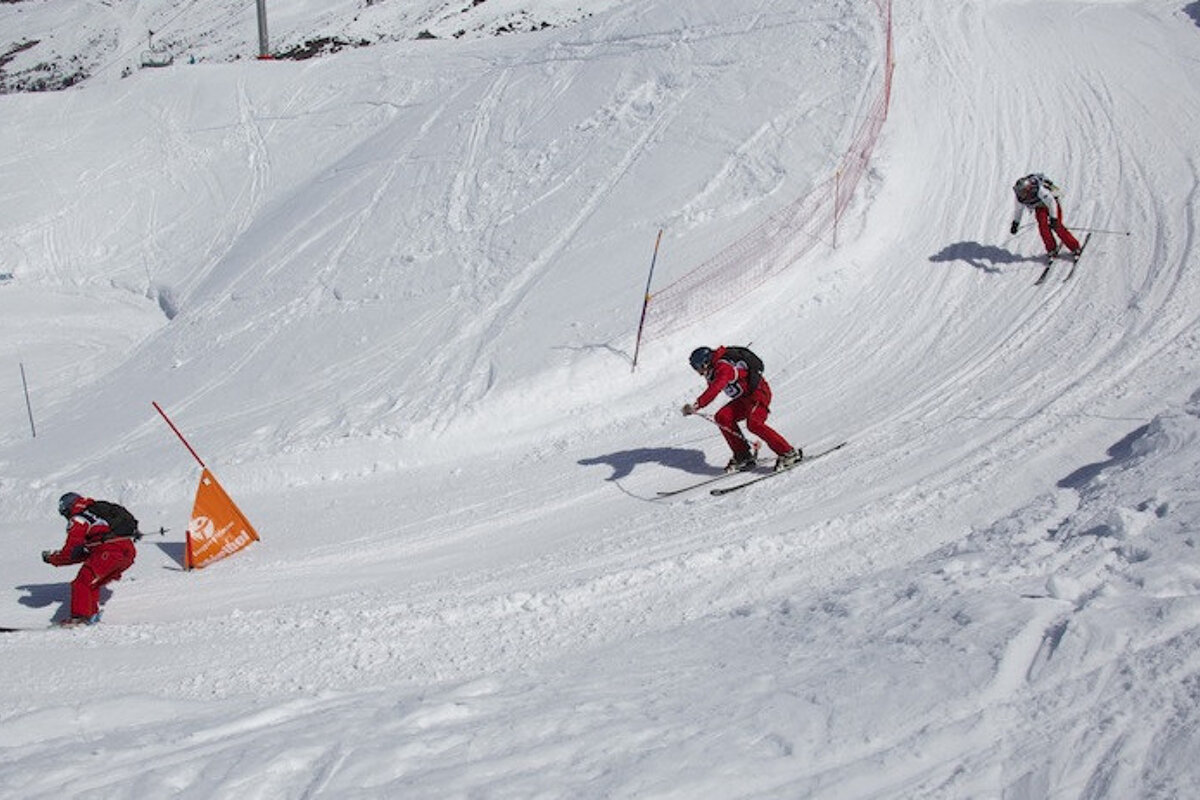 Skiers are skiing down a snowy slope with a sign that says ' allianz ' on it