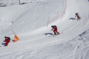 Skiers are skiing down a snowy slope with a sign that says ' allianz ' on it