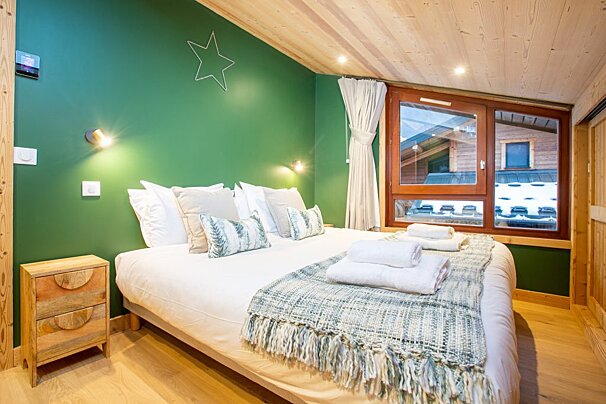 A bedroom with a large bed and a green wall