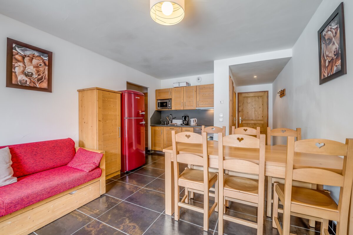 A living room with a red refrigerator and a table and chairs