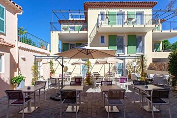A patio with tables and chairs and umbrellas in front of a building