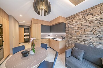 A kitchen with a table and chairs and a stone wall