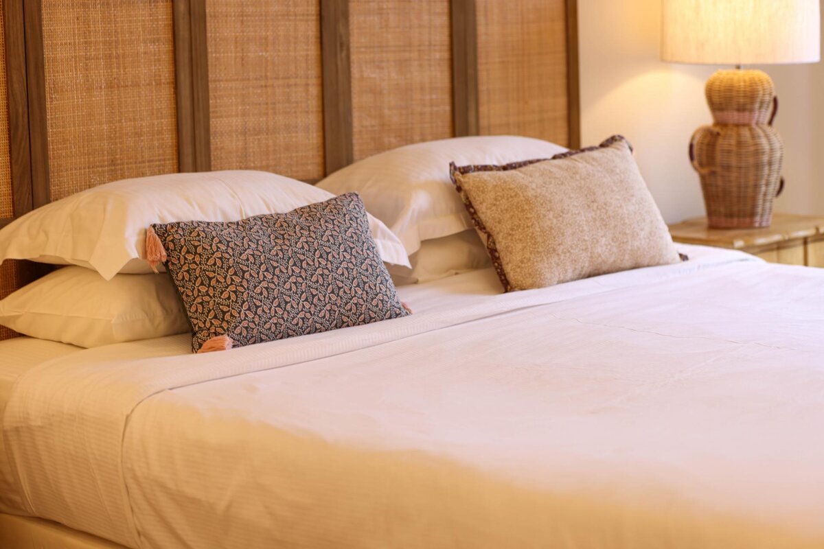 A bed with white sheets and pillows and a lamp