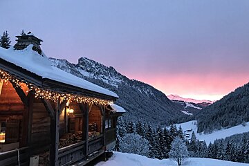 A snowy cabin with a sunset in the background