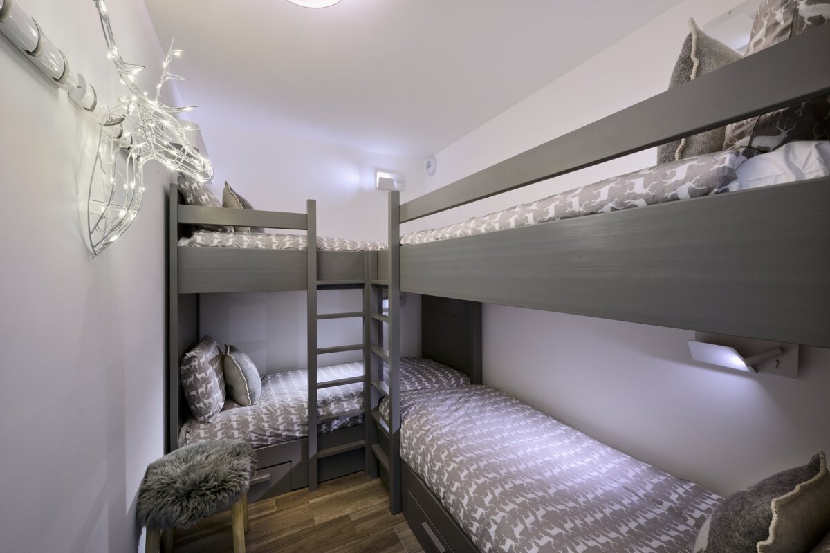 Three bunk beds in a small room with a deer decoration on the wall