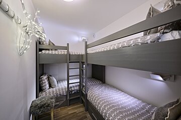 Three bunk beds in a small room with a deer decoration on the wall