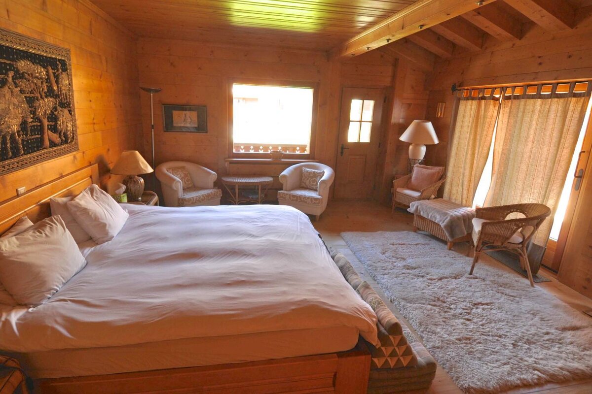 A bedroom with a large bed and two chairs