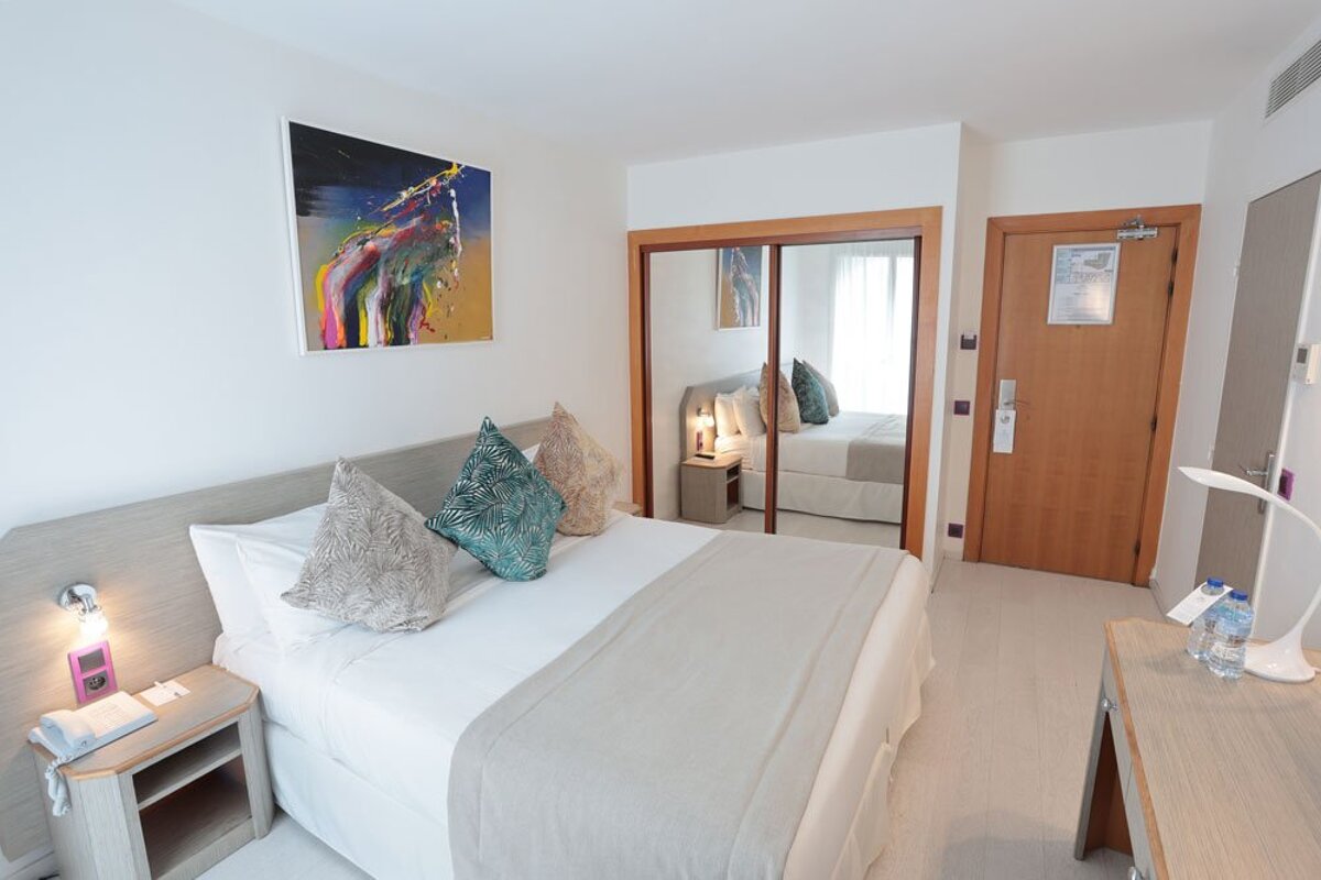 A hotel room with a painting on the wall above the bed