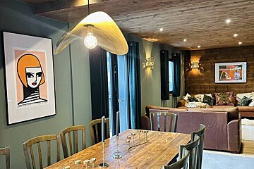 A dining room with a table and chairs and a painting on the wall