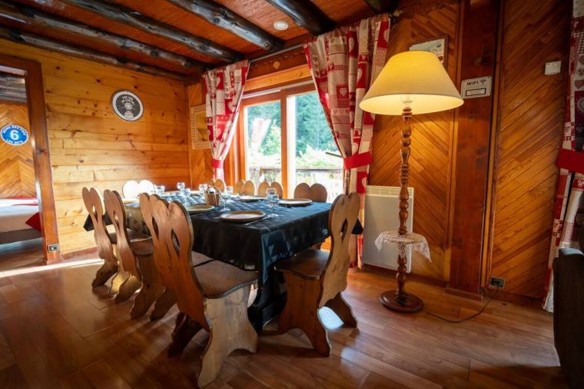 A wooden dining room with a table and chairs and a lamp