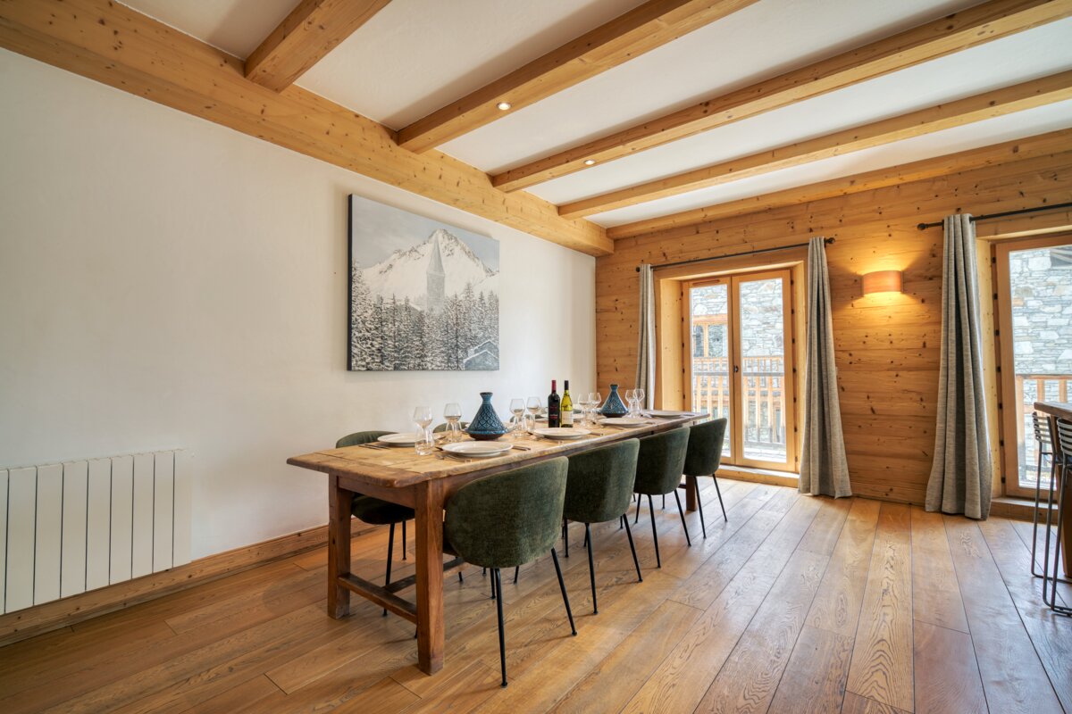 A dining room with a table and chairs and a painting on the wall
