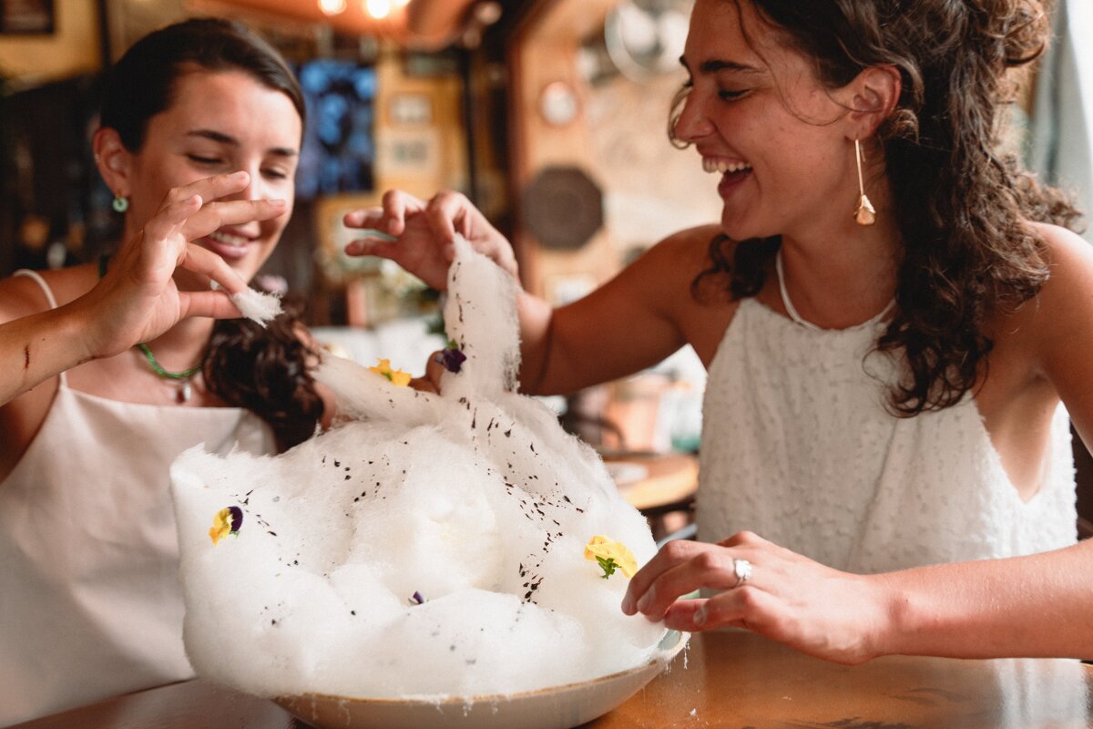 Two women are playing with a bowl of cotton candy