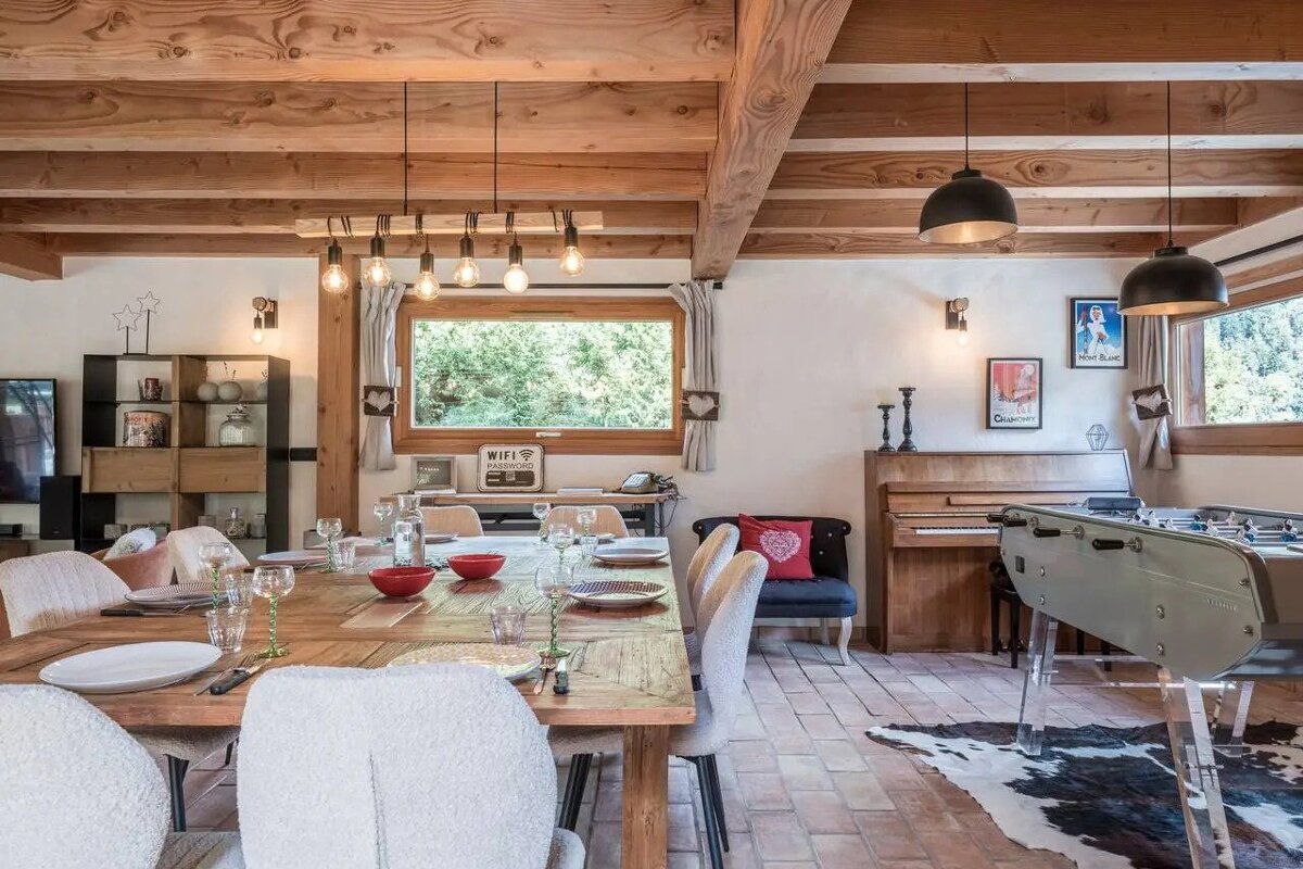 A dining room with a large wooden table and chairs