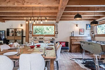 A dining room with a large wooden table and chairs