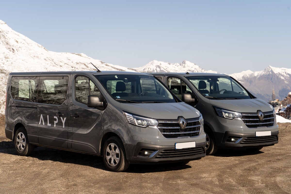 Two alpy vans are parked next to each other