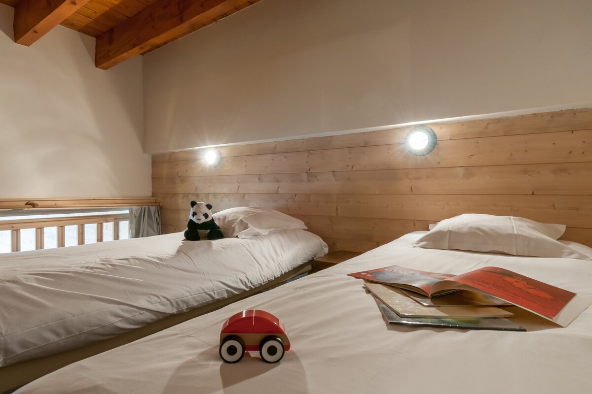 A toy car sits on a bed next to a book