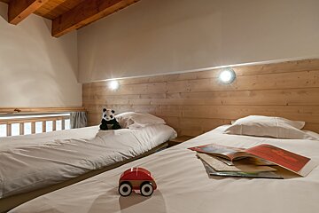 A toy car sits on a bed next to a book