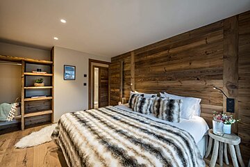 A bedroom with a wooden wall and a bed with a fur blanket