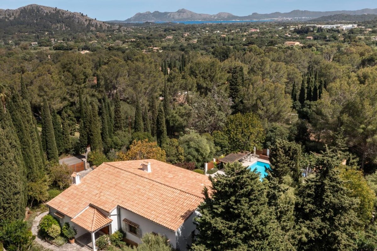 An aerial view of a house surrounded by trees and mountains