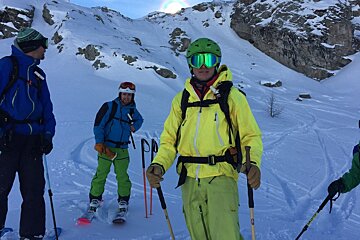 A man in a yellow jacket is standing in the snow