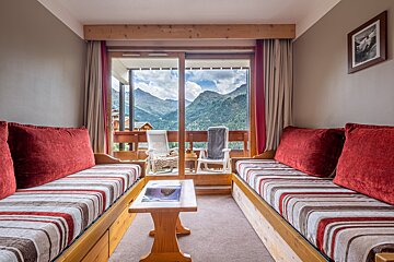 A living room with a couch and a table with mountains in the background