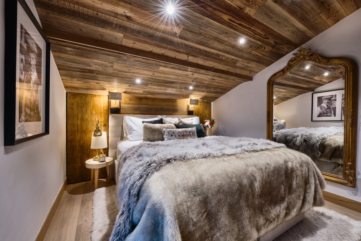 A bedroom with a bed and a large mirror