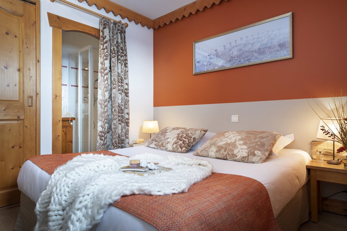 A bedroom with a painting on the wall above the bed