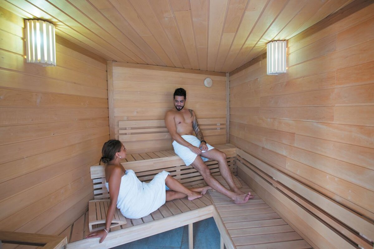 A man and a woman are wrapped in towels in a sauna