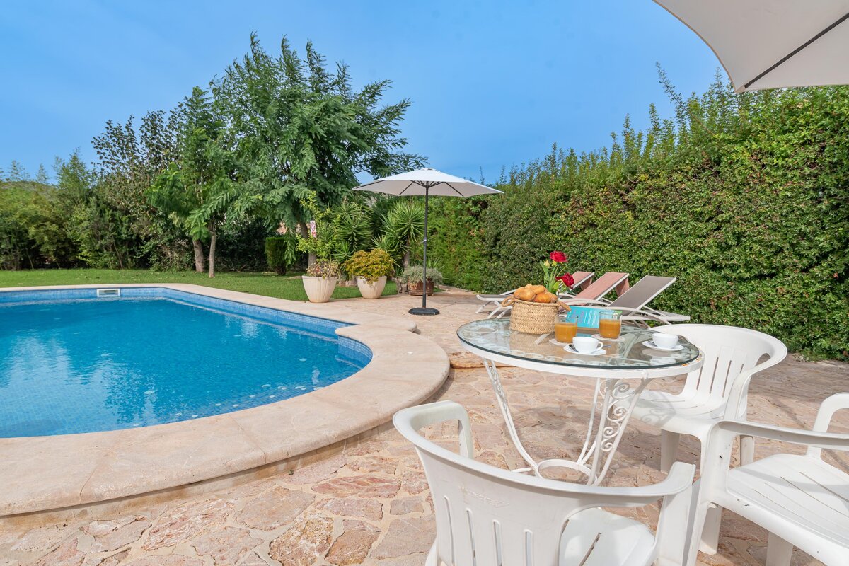 A swimming pool with a table and chairs in front of it