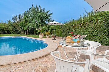 A swimming pool with a table and chairs in front of it