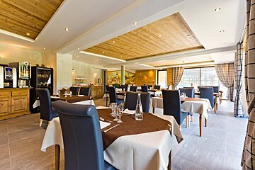 A dining room with tables and chairs and a painting on the wall