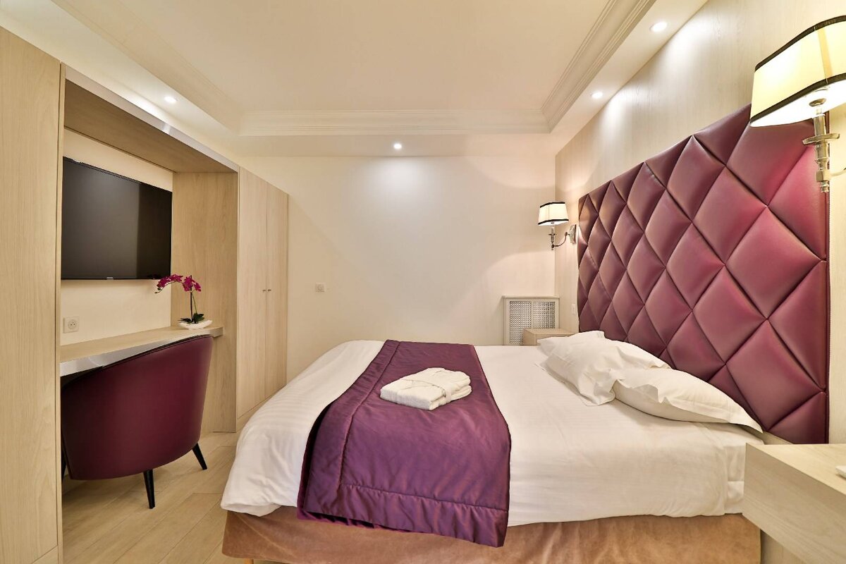 A hotel room with a purple headboard and a purple chair