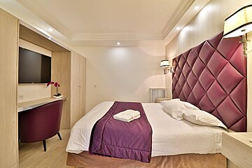 A hotel room with a purple headboard and a purple chair