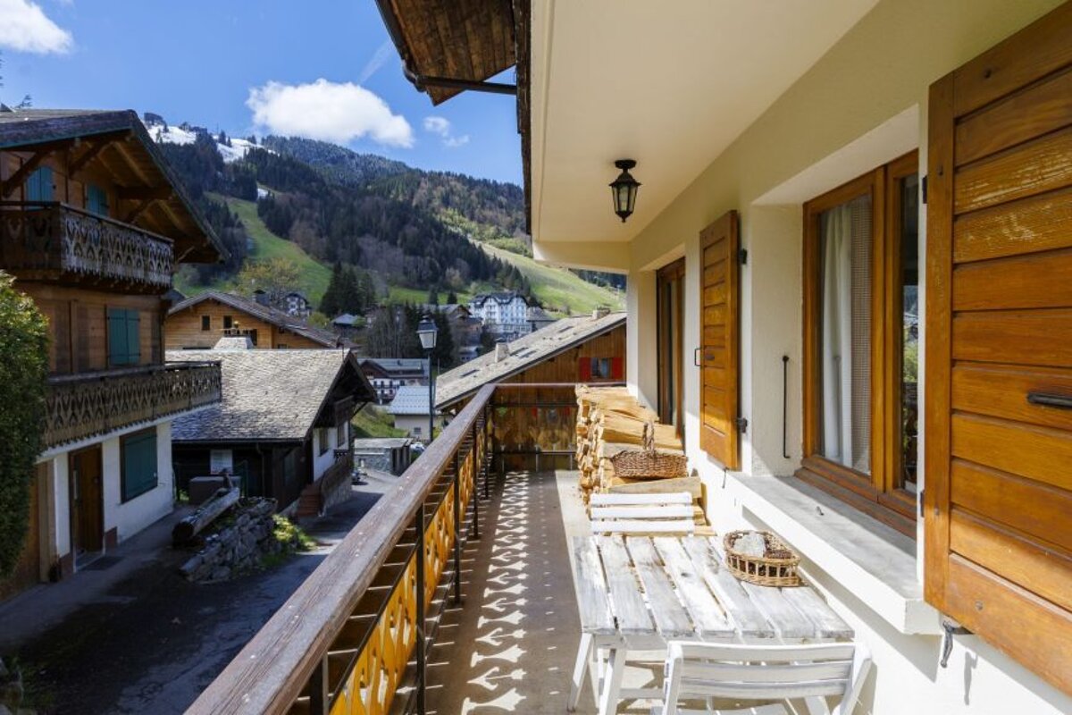 A balcony with a table and chairs and a view of the mountains