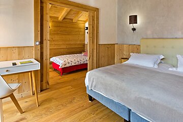 A bedroom with two beds and a desk with a book on it