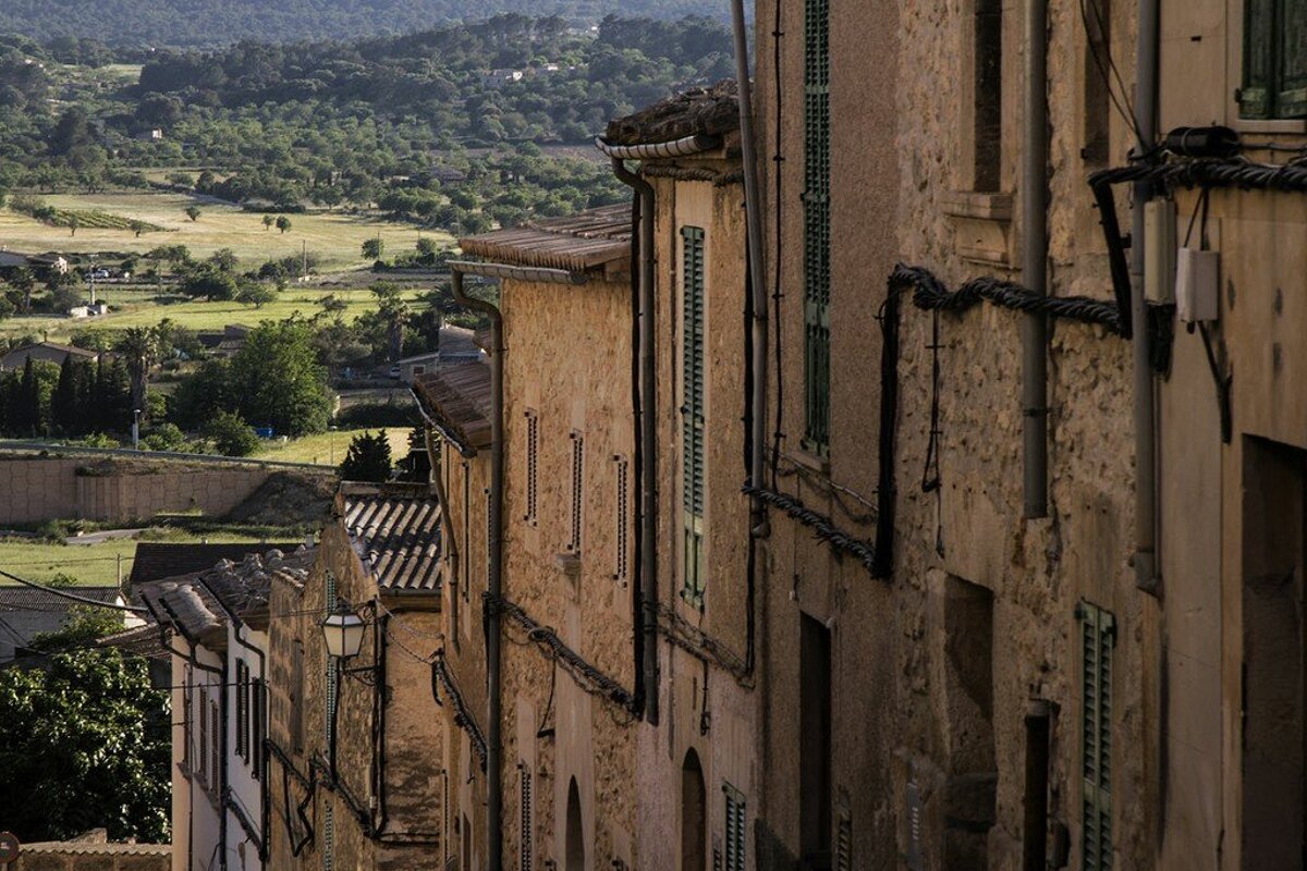 A narrow street with a view of a valley behind it