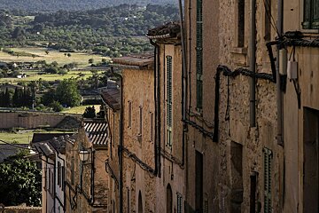 A narrow street with a view of a valley behind it