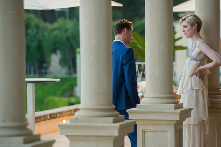 A man in a blue suit stands next to a woman in a white dress