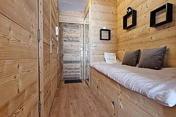 A wooden hallway with a bench and pillows and a bag that says