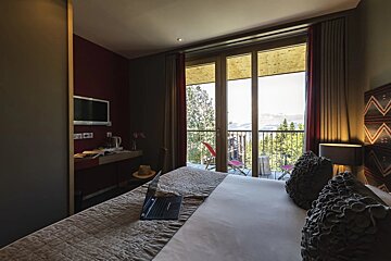 A hotel room with a large window and a laptop on the bed